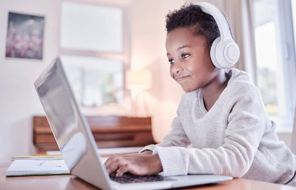 He who laughs most, learns best. Shot of a young boy doing his homework on a laptop at home. — Stock Photo, Image