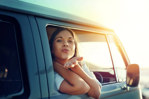 Vemo-nos quando eu voltar. Tiro de uma jovem mulher inclinada para fora de uma janela de vans e soprando um beijo em uma viagem de carro. — Fotografia de Stock
