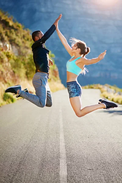 Theyre pumped up for fitness. Shot of a sporty young couple high fiving each other in midair outside. — Stock Photo, Image