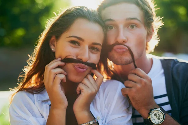 Nous vous moustachons si vous remarquez quelque chose de différent chez nous. Portrait d'un jeune couple profitant d'un moment stupide ensemble tout en collant à l'extérieur. — Photo
