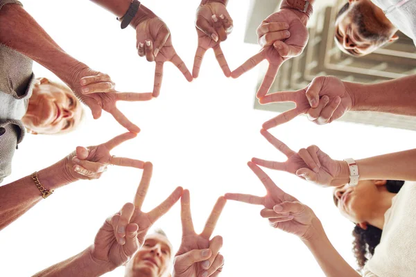 Were shooting for the stars. Low angle shot of a group of unrecognisable people making a peace sign with their fingers to create a star shape together. —  Fotos de Stock