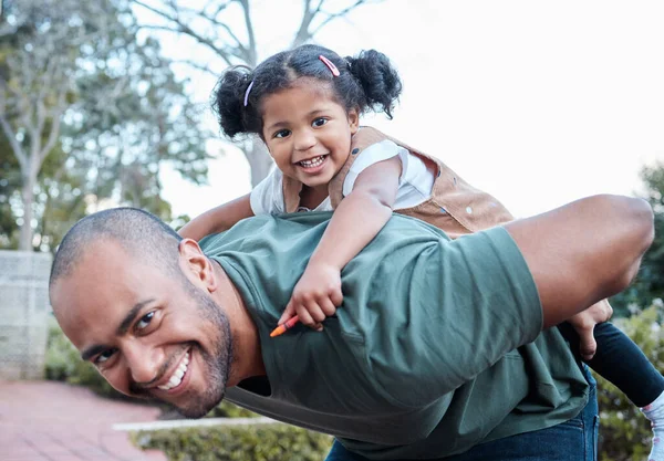 Estavam sempre com disposição para se divertirem. Tiro de um homem carregando sua filha de costas enquanto estava de pé fora. — Fotografia de Stock