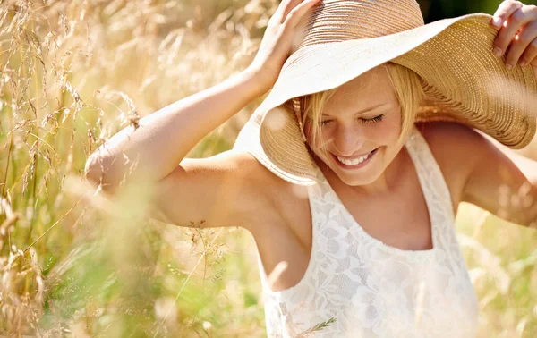 Roligt under solen. Skjuten av en vacker ung kvinna i en solhatt går genom högt gräs. — Stockfoto