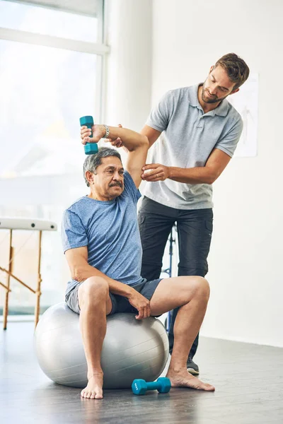 Något obehag alls. Full längd skott av en ung manlig sjukgymnast bistå en äldre patient i tillfrisknandet. — Stockfoto