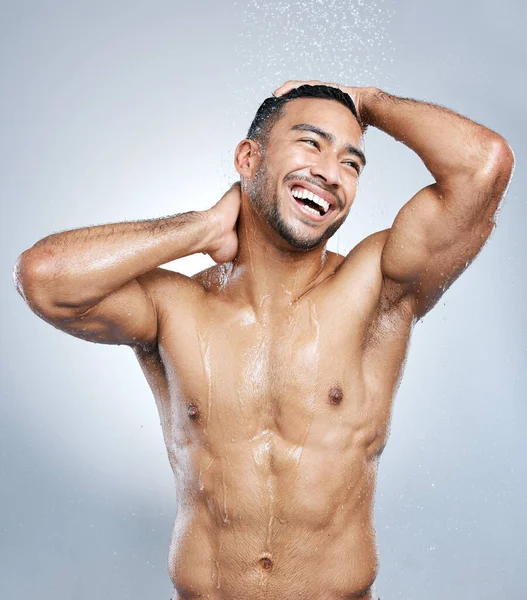 Abyste vypadali dobře, musíte si procvičit dobrou hygienu. Studio záběr pohledný mladý muž, jak se sprchuje na šedém pozadí. — Stock fotografie