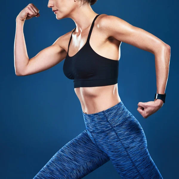 Ponerse en forma es todo sobre el trabajo que haces. Estudio de una mujer en forma irreconocible posando sobre un fondo azul. —  Fotos de Stock