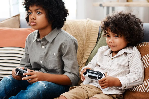 Seine Spielzeit. Schnappschuss von zwei entzückenden kleinen Jungen, die auf einem Sofa sitzen und zu Hause zusammen Videospiele spielen. — Stockfoto