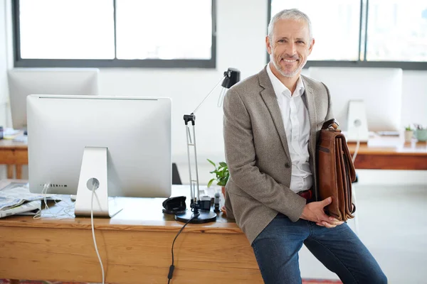 Es war ein sehr guter Tag im Büro. Porträt eines lässig gekleideten reifen Geschäftsmannes, der auf seinem Schreibtisch in einem Büro sitzt. — Stockfoto