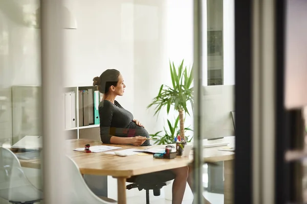 Refletindo sobre a vida e o trabalho. Tiro de uma mulher de negócios grávida sentada em seu escritório. — Fotografia de Stock