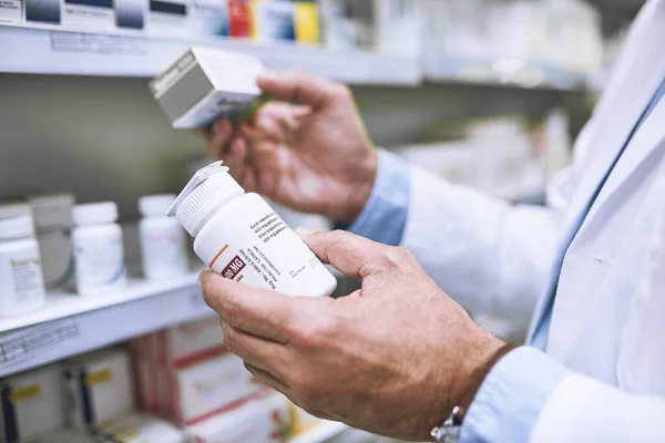 Take these three times a day. Shot of a unrecognizable pharmacist holding two different medication boxes each in one hand in a pharmacy. — Stock Photo, Image