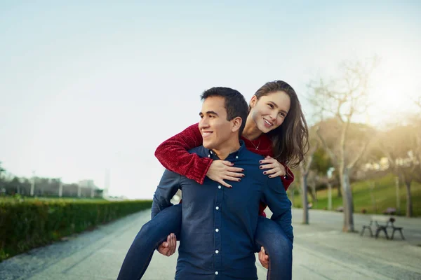Kärlek är precis vad världen behöver. Skjuten av ett lyckligt ungt par njuter av en piggyback rida utomhus. — Stockfoto