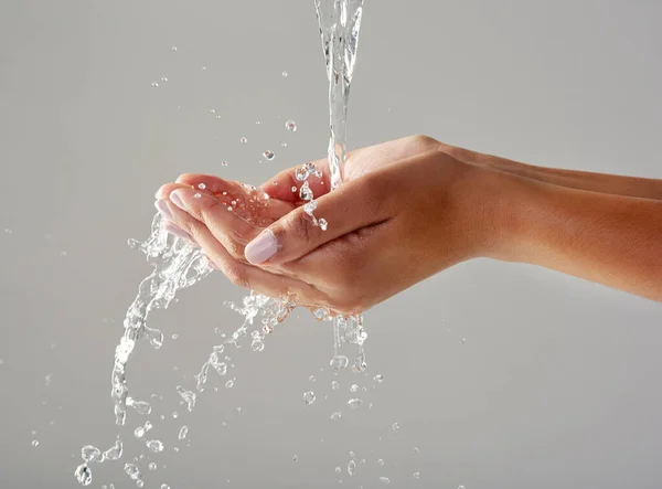Kemurnian di telapak tangan Anda. Potret tangan dipotong di bawah aliran air dengan latar belakang abu-abu. — Stok Foto