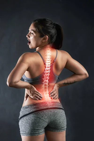 A lesão é sempre um risco no desporto. Rearview tiro de uma jovem esportista segurando suas costas em angústia depois de feri-lo. — Fotografia de Stock