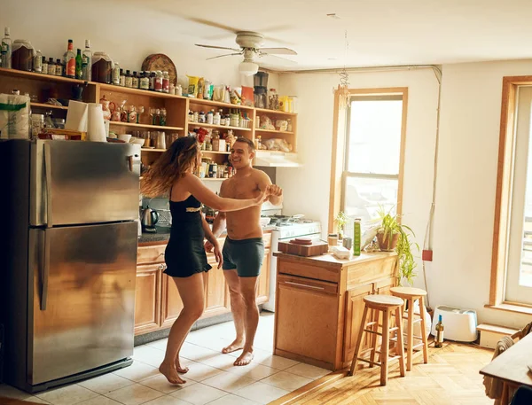 Encha uma casa com amor e torne-a um lar. Tiro de um jovem casal feliz dançando na cozinha em casa. — Fotografia de Stock