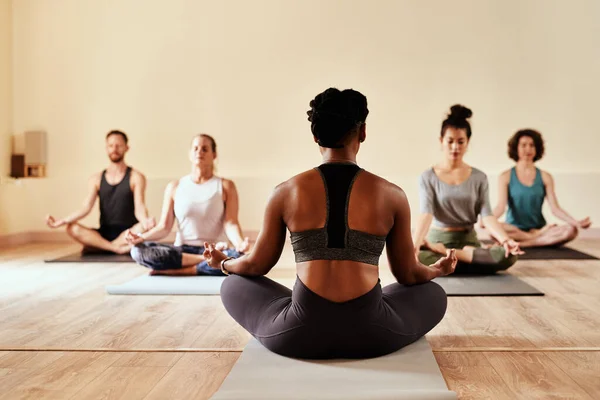 Cuando creas, recibirás. Fotografía de un grupo de jóvenes hombres y mujeres meditando en la posición de loto durante una sesión de yoga. — Foto de Stock
