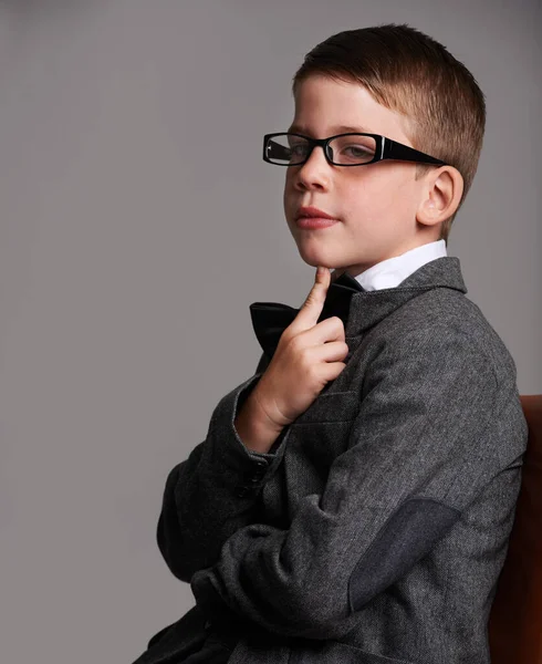 É uma grande cómoda. Estúdio tiro de um menino bonito vestindo um terno retro contra um fundo cinza. — Fotografia de Stock