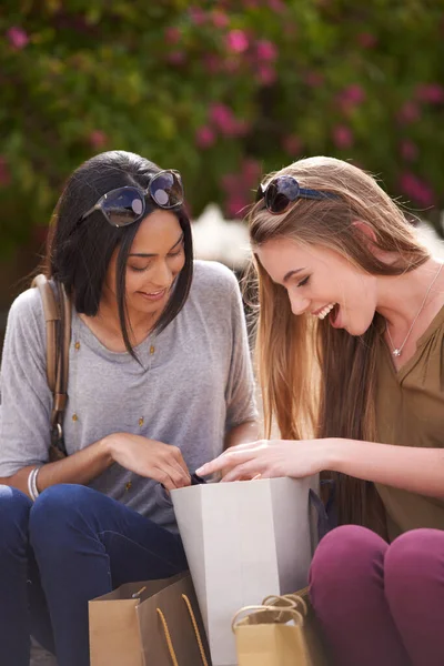 Montre et raconte. Deux jeunes femmes admirant leurs trouvailles de shopping. — Photo