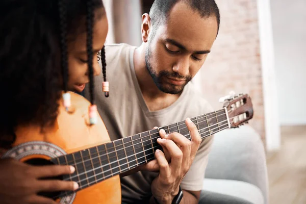 Um amor paterno é uma doce melodia. Tiro de uma jovem aprendendo a tocar guitarra com seu pai em casa. — Fotografia de Stock