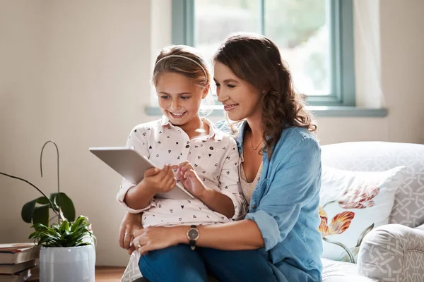 Η τεχνολογία είναι ένα μεγάλο εργαλείο για να ενθαρρύνει τη μάθηση. Φωτογράφηση ενός αξιολάτρευτου μικρού κοριτσιού χρησιμοποιώντας ένα ψηφιακό tablet με τη μητέρα της στο σπίτι. — Φωτογραφία Αρχείου