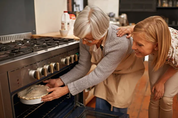 Uuniin. Laukaus kaunis nuori nainen oppimisen leivonta vinkkejä hänen isoäitinsä. — kuvapankkivalokuva