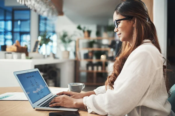 U kunt online meer te weten komen over mijn bedrijf. Shot van een zakenvrouw met behulp van haar laptop tijdens het werken in een cafe. — Stockfoto