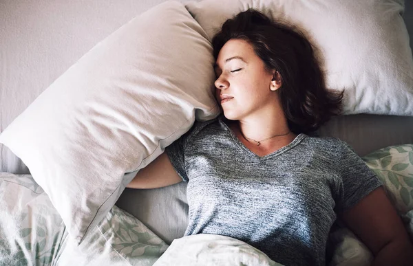 Få lite välbehövlig vila. Hög vinkel skott av en attraktiv ung kvinna sover på sin säng på morgonen hemma. — Stockfoto