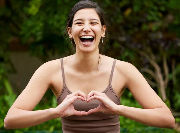 Йога это обретение близости к хорошим вибрациям. Портрет молодой женщины, которая придает форму сердцу руками во время занятий на открытом воздухе. — стоковое фото