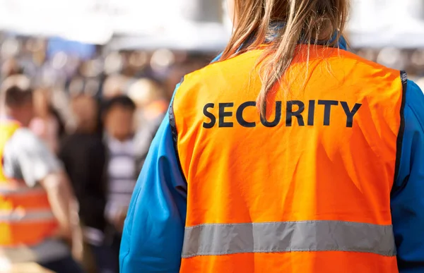 Safety is the main aim. Rearview shot of a security officer standing outdoors with a crowd in the background. — стоковое фото