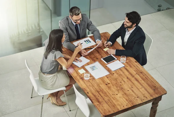 Éxito su prioridad número uno. Disparo de tres colegas sentados alrededor de una tableta de reuniones en la oficina. — Foto de Stock