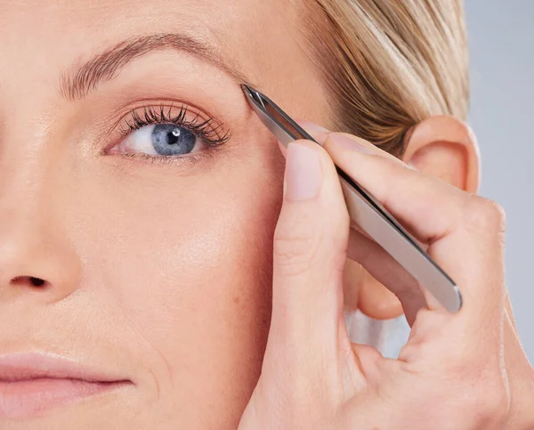 Parfaitement en forme. Portrait en studio d'une jolie jeune femme qui arrache les sourcils sur un fond gris. — Photo