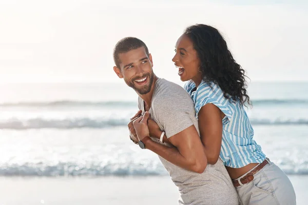 Att tillbringa en ljus dag uppslukad av kärlek. Skjuten av ett ungt par njuter av lite kvalitetstid tillsammans på stranden. — Stockfoto