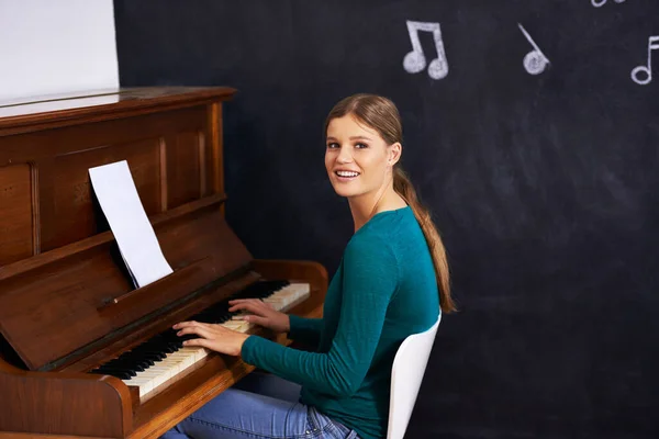 Usando ilustrações para ensinar seus alunos. Tiro de uma mulher tocando piano contra um fundo de notas musicais. — Fotografia de Stock