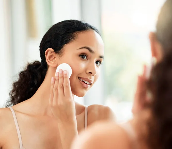 Yüzünü temiz tut. Evdeki bir banyoda yüzünü temizlemek için pamuk ped kullanan genç bir kadının fotoğrafı.. — Stok fotoğraf