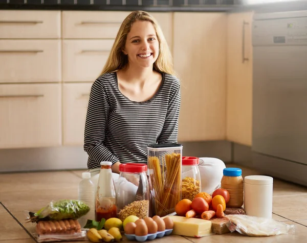 Lets get to cooking. Shot of an attractive young woman surrounded by various food in the kitchen at home. — Foto de Stock