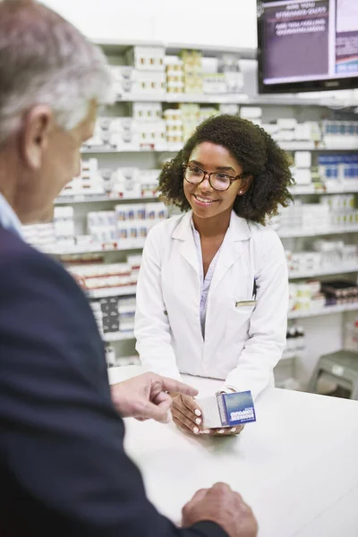 Ez az, amit keresel. Egy vidám fiatal női gyógyszerészt, aki receptre kapható gyógyszereket ad egy gyógyszertárban.. — Stock Fotó