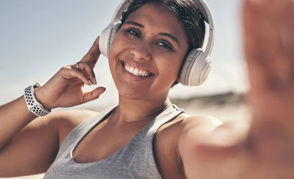 Exercise makes you feel good, the benefits are obvious. Shot of a young woman wearing headphones while out for a workout. — 스톡 사진