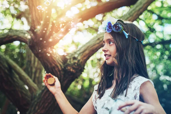 They look just like fairies. Shot of a little girl catching fireflies in a jar outside. — Photo