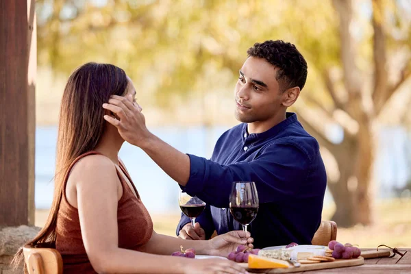 Sitting next to her is always the best seat in the house. Shot of a young couple having wine on a date on a wine farm. —  Fotos de Stock