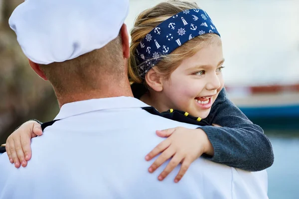 Těším se, až bude mít tatínka doma. Zpětný pohled záběr otce v námořní uniformě objímající jeho šťastnou holčičku. — Stock fotografie