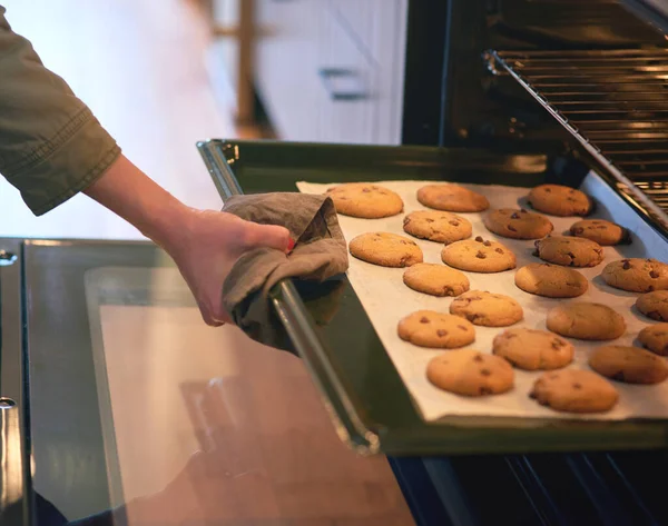 Niente puzza meglio dei biscotti fatti in casa. Colpo ritagliato di una donna irriconoscibile che estrae biscotti da un forno. — Foto Stock