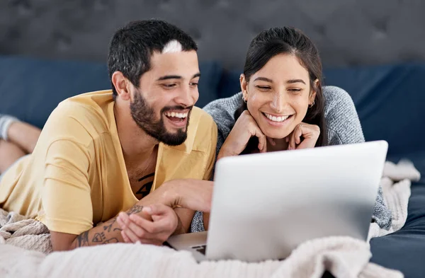 Vamos a relajarnos en casa y ver películas. Fotografía de una pareja joven usando un ordenador portátil juntos en la cama. —  Fotos de Stock