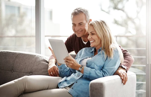 Hacen tiempo de pantalla en pareja. Foto de una pareja adulta usando una tableta digital mientras se relajan juntos en el sofá en casa. —  Fotos de Stock