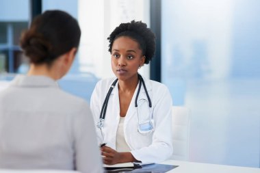 Bilmem gereken herhangi bir belirti var mı? Kadın bir doktorun, ofisinde bir hastayla konuşurken çekilmiş bir fotoğrafı..