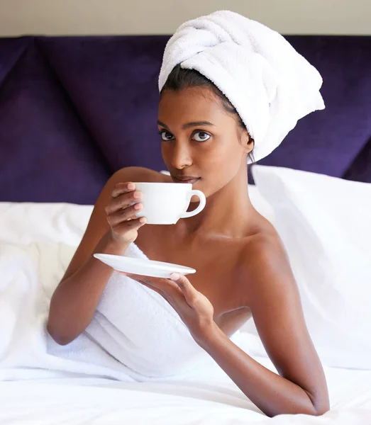 Je to perfektní začátek každé dovolené. Oříznutý portrét atraktivní mladé ženy pití čaje, zatímco leží na posteli po sprše. — Stock fotografie