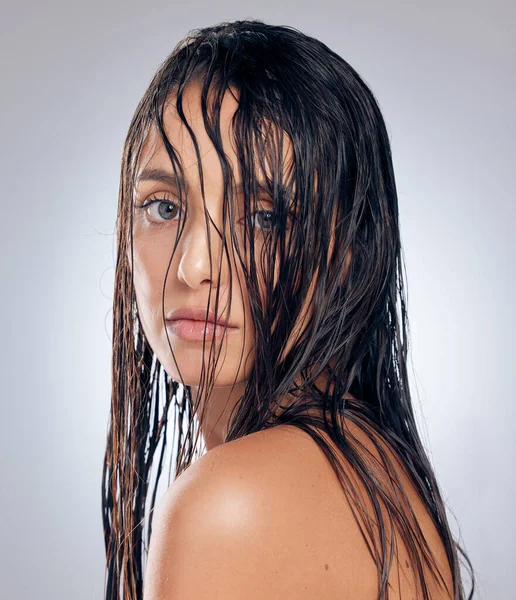I wear my hair however I want to. Shot of an attractive young woman standing alone in the studio and posing with wet hair. — стоковое фото