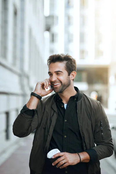 Estoy pasando el día en la ciudad. Recortado disparo de un joven guapo haciendo una llamada telefónica mientras viajaba por la ciudad. — Foto de Stock