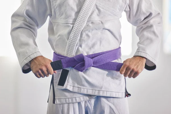 Je suis une ceinture violette. Plan recadré d'un homme méconnaissable attachant une ceinture violette autour de sa taille alors qu'il était en plein jiu jitsu gi. — Photo
