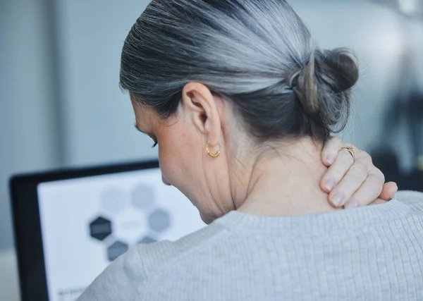 I have a knot in my neck. Shot of a mature businesswoman sitting alone in the office and suffering from a sore neck. — Stock Photo, Image