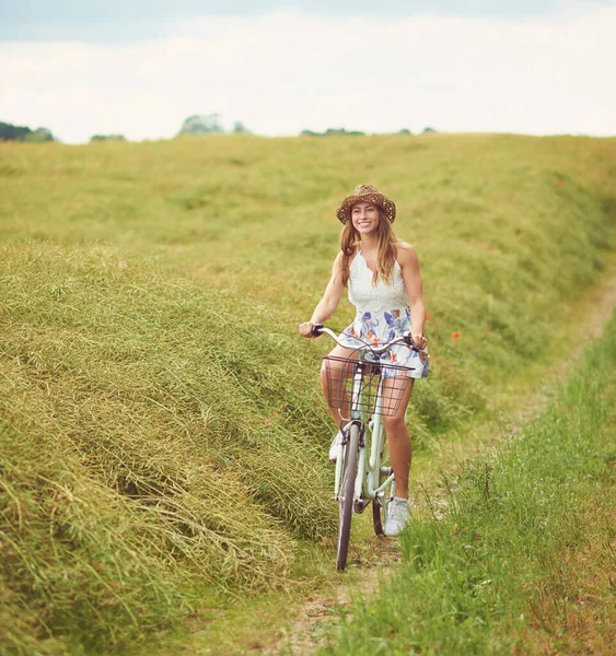 The city is exciting, but the country is beautiful. Shot of a young woman cycling through the countryside. — Foto de Stock