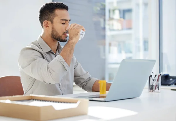 De energieniveaus zijn hoog. Foto van een jongeman die zijn laptop gebruikt en koffie drinkt op het werk in een modern kantoor. — Stockfoto
